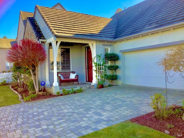 view of front of house with a garage, fence, decorative driveway, and stucco siding