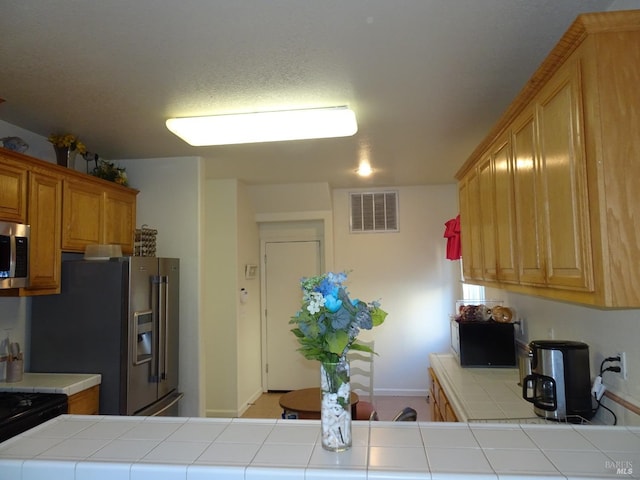 kitchen with tile countertops and appliances with stainless steel finishes