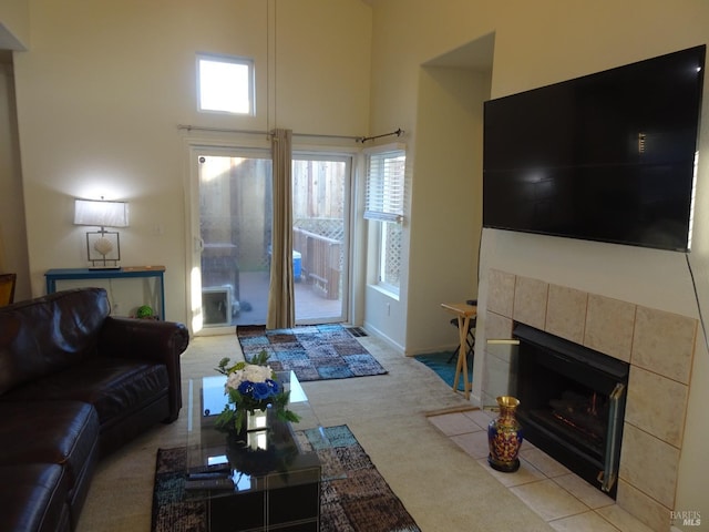 living room featuring a tiled fireplace and a high ceiling