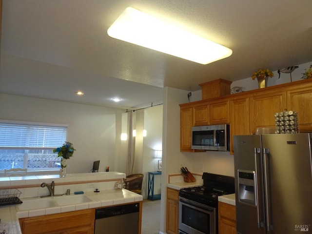 kitchen with appliances with stainless steel finishes, sink, and tile countertops