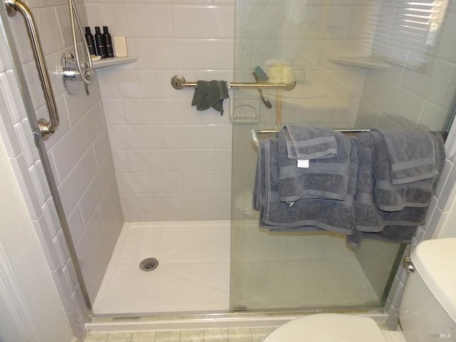 bathroom featuring toilet and a shower with shower door