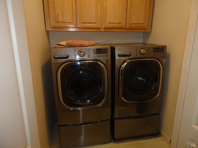 clothes washing area with cabinets and washing machine and clothes dryer