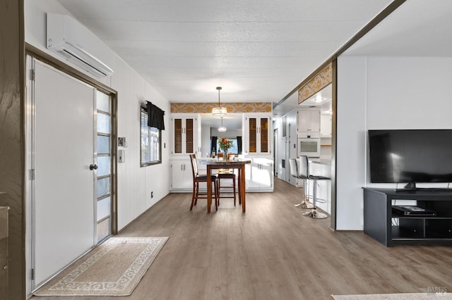 dining space with a wall mounted air conditioner and wood-type flooring