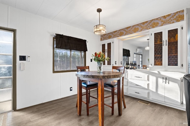 dining area with a wall mounted air conditioner, a chandelier, and dark hardwood / wood-style floors