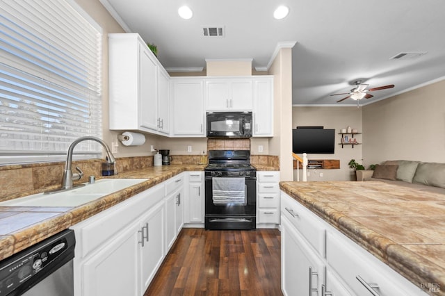 kitchen with black appliances, ornamental molding, white cabinets, and a sink