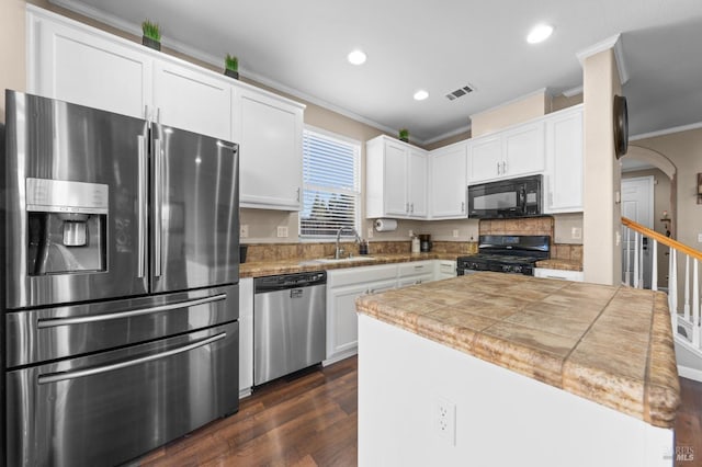 kitchen featuring arched walkways, crown molding, visible vents, white cabinets, and black appliances