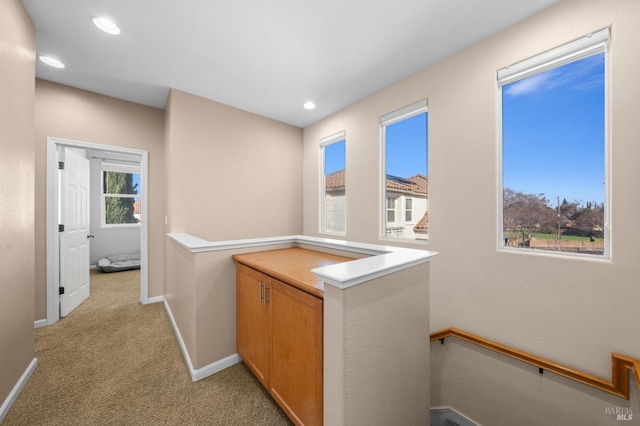 corridor featuring recessed lighting, baseboards, light colored carpet, and an upstairs landing