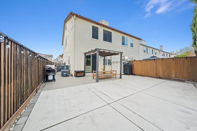 rear view of property with a fenced backyard, a chimney, a patio area, a pergola, and stucco siding