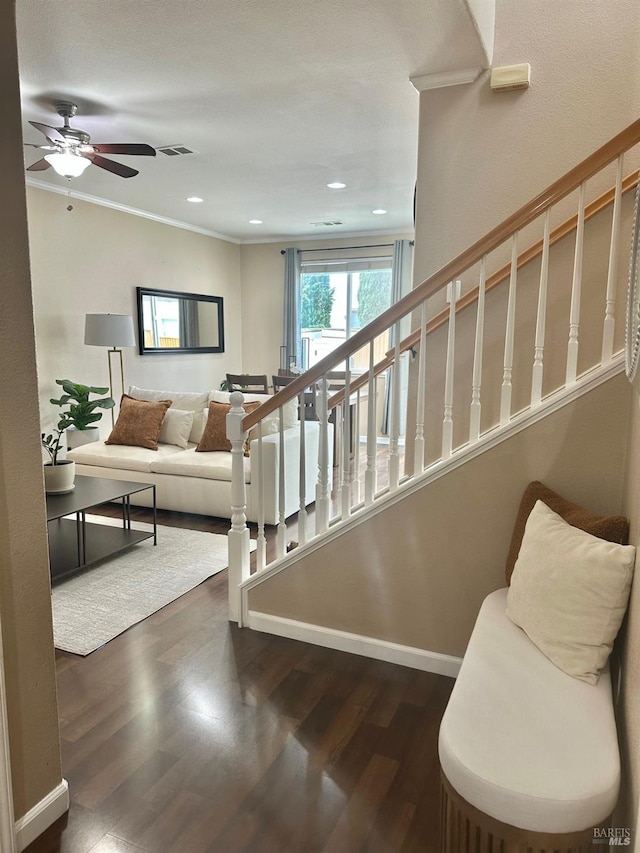 staircase featuring ornamental molding, visible vents, baseboards, and wood finished floors