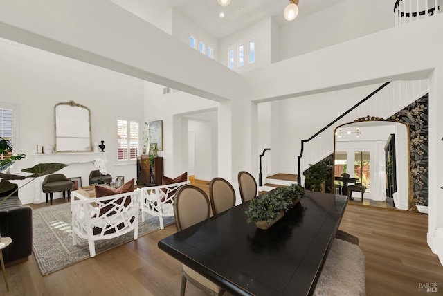 dining space with hardwood / wood-style flooring, plenty of natural light, and a high ceiling