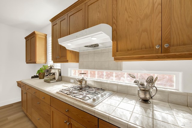 kitchen featuring light wood-type flooring, tile countertops, and gas stovetop