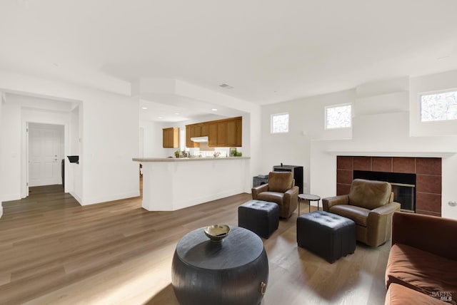 living room with a healthy amount of sunlight, hardwood / wood-style flooring, and a tile fireplace