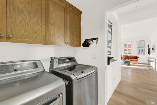 laundry area with washer and dryer, cabinets, and light wood-type flooring