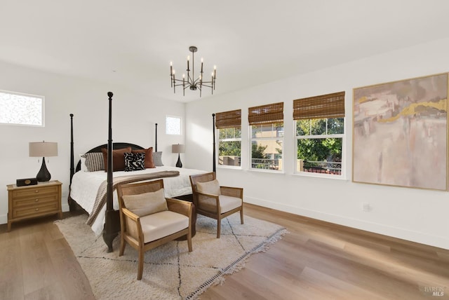 bedroom featuring wood-type flooring, a chandelier, and multiple windows