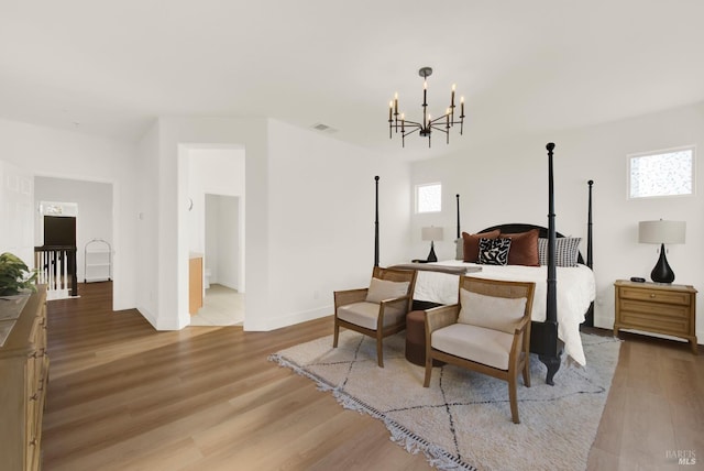 bedroom featuring a notable chandelier, connected bathroom, hardwood / wood-style flooring, and multiple windows