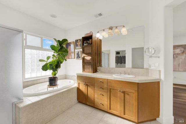 bathroom with tiled bath, tile patterned floors, and vanity