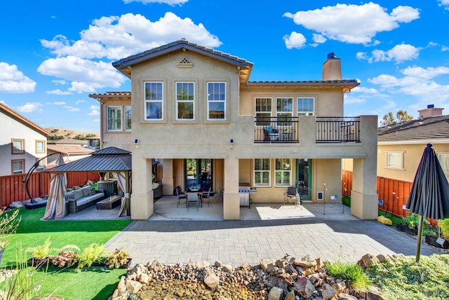 back of house featuring a balcony, a gazebo, a lawn, a patio, and an outdoor living space