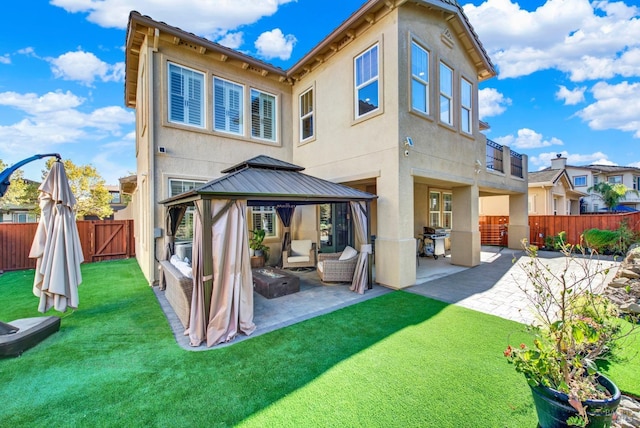 back of property featuring a gazebo, a lawn, and a patio