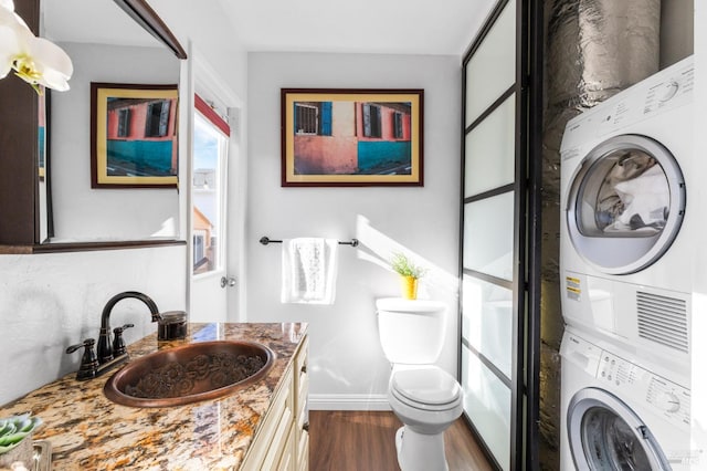 bathroom featuring stacked washer and dryer, wood-type flooring, toilet, and vanity