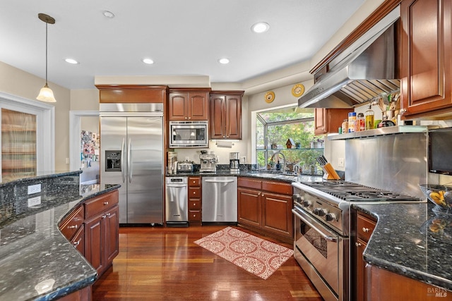 kitchen featuring decorative light fixtures, extractor fan, sink, built in appliances, and dark wood-type flooring