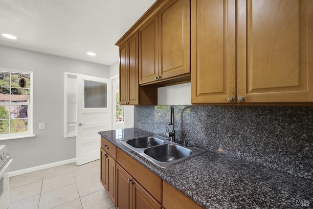 kitchen featuring dark stone countertops, sink, backsplash, and light tile patterned floors