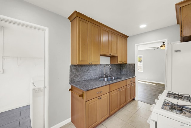 kitchen featuring sink, light tile patterned floors, ceiling fan, white appliances, and backsplash