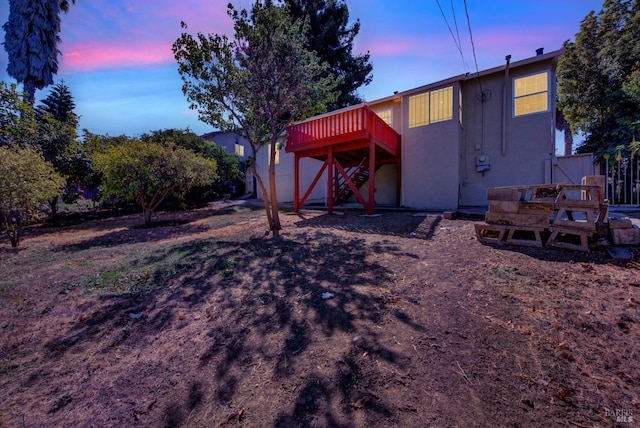 back house at dusk with a wooden deck