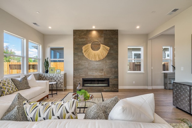 living room featuring wood-type flooring and a tiled fireplace