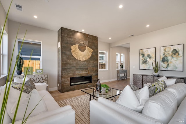 living room featuring a tile fireplace and light hardwood / wood-style floors