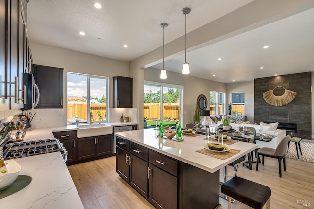 kitchen featuring decorative light fixtures, a center island, sink, appliances with stainless steel finishes, and light stone counters