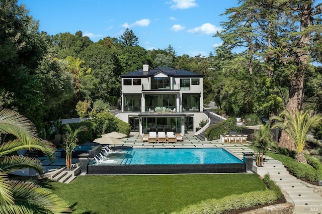 back of house with a balcony, a patio area, an outdoor living space, and a lawn