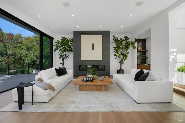 living room with a tiled fireplace, recessed lighting, and wood finished floors