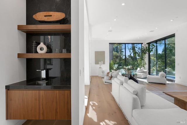 living room with floor to ceiling windows, light hardwood / wood-style floors, and bar area