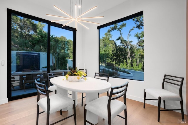 dining room with an inviting chandelier, baseboards, light wood-type flooring, and a wealth of natural light