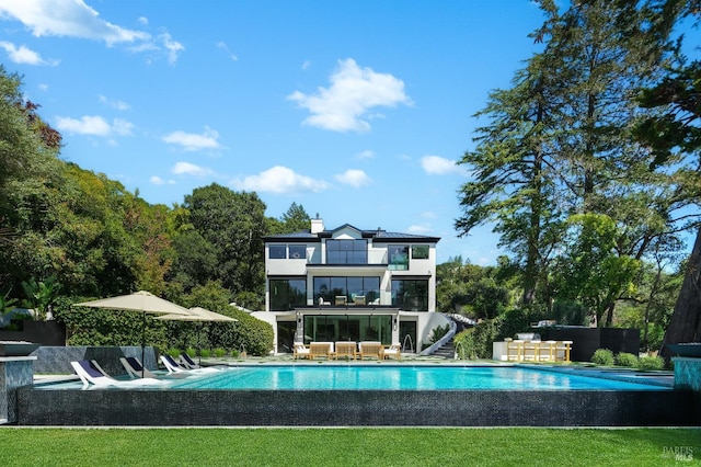 rear view of house featuring an outdoor living space, a patio, a balcony, and a fenced in pool