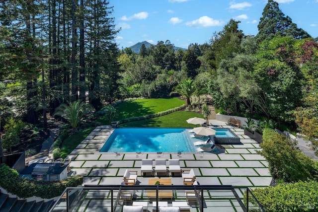 outdoor pool with a yard, a patio, and a mountain view