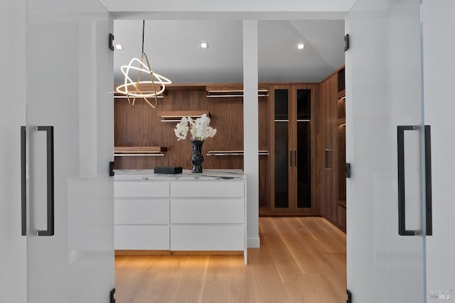 spacious closet featuring light wood-style floors and an inviting chandelier
