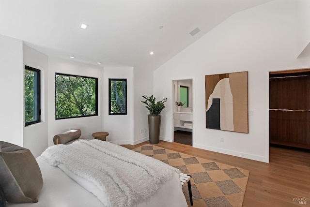 bedroom with a walk in closet, recessed lighting, baseboards, wood finished floors, and lofted ceiling