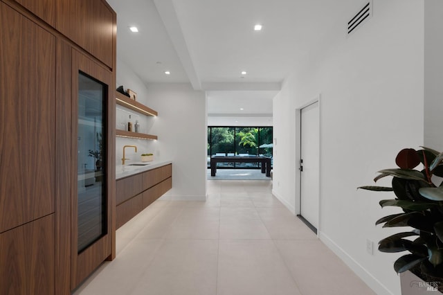 hallway with beamed ceiling, light tile patterned flooring, and sink