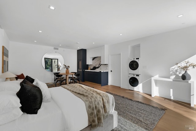 bedroom with stacked washer and clothes dryer and hardwood / wood-style flooring