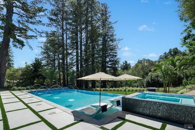 outdoor pool with an in ground hot tub and a patio area