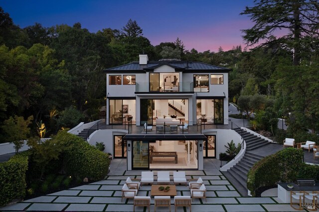 back house at dusk with an outdoor hangout area, a patio area, and a balcony