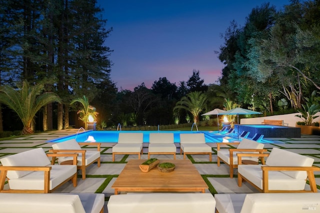 pool at dusk with a patio area and outdoor lounge area