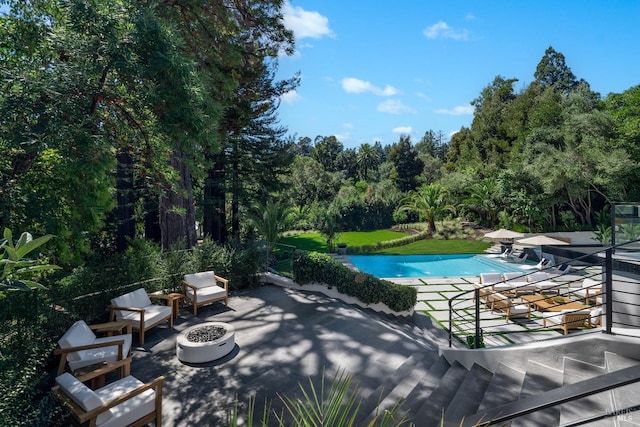 view of swimming pool featuring a patio and a fire pit