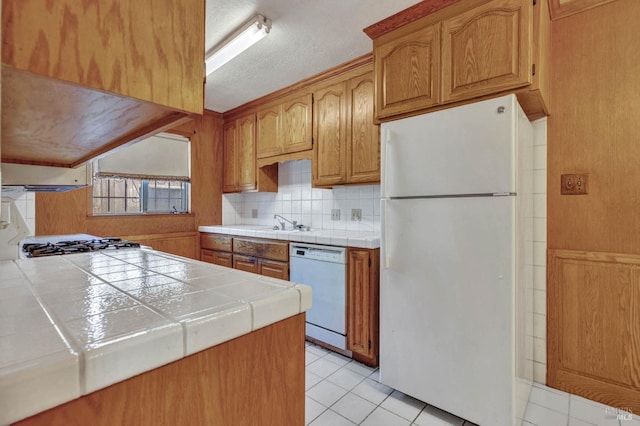 kitchen featuring white appliances, light tile patterned floors, tile countertops, and tasteful backsplash