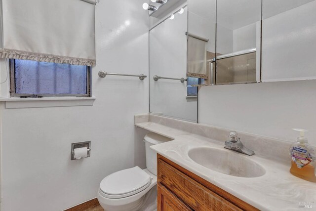 bathroom featuring toilet, a shower with shower door, and vanity