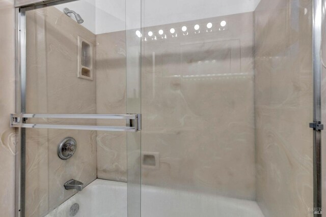 bathroom featuring bath / shower combo with glass door