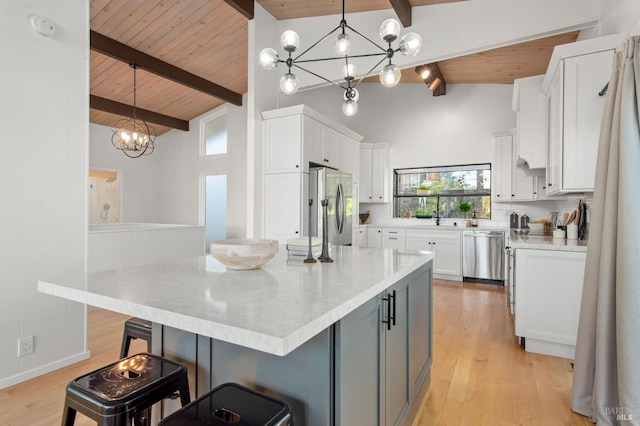 kitchen featuring stainless steel appliances, white cabinetry, hanging light fixtures, and beam ceiling