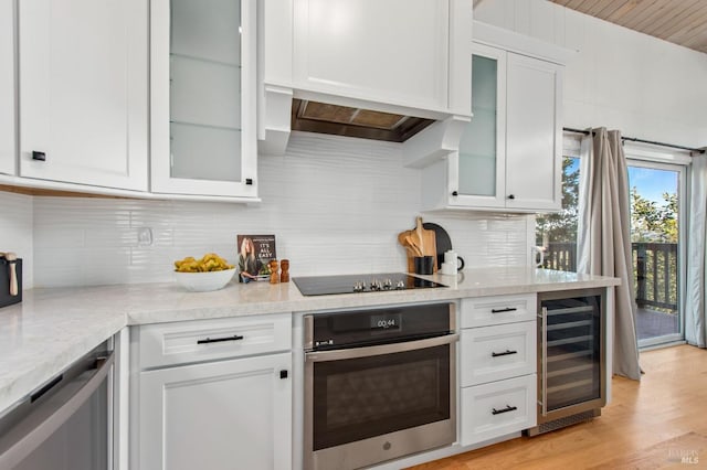 kitchen featuring light hardwood / wood-style flooring, wine cooler, black electric stovetop, white cabinets, and oven