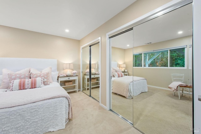 bedroom featuring multiple closets and light carpet